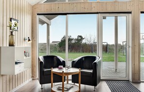 Relax in this serene space with a patio view, featuring a comfortable seating area and shelving unit.