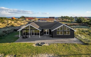 Relax in a covered patio area with scenic views of the nearby beach and dunes.