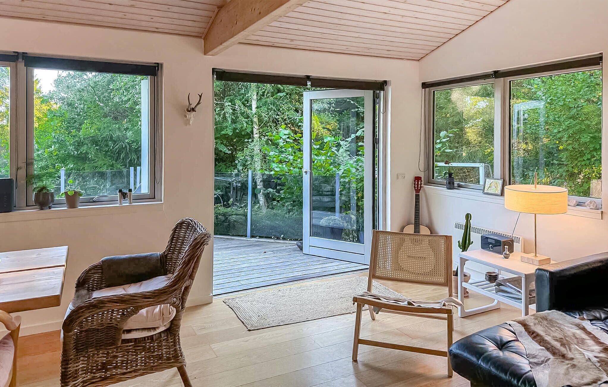Una habitación acogedora con muebles de mimbre, una guitarra y vistas al exterior, lleno de vegetación.