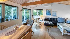 A cozy living room with a wooden table, a sofa, and a dining area with a table and chairs.