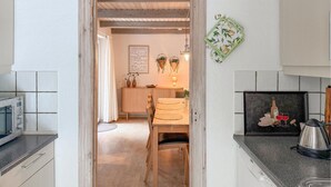 Et køkken med mikroovn, vask og spiseplads med bord og stole.