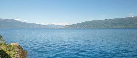 A calm lake with a rocky shoreline and distant mountains.