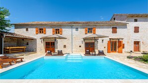 Ein Gebäude aus Stein mit Pool, Sitzgelegenheiten im Freien und Holzhörnern.