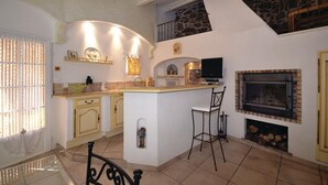A kitchen with a central island, a fireplace, and a stone staircase. - Amazing home in Bedousse (Bedousse)