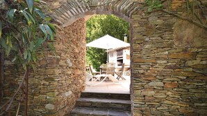 A stone archway leading to a patio area with outdoor furniture and a grill. - Amazing home in Bedousse (Bedousse)