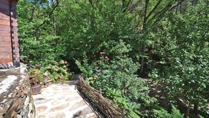 A stone pathway leading to a wooden cabin surrounded by lush greenery and flowering plants. - Amazing home in Bedousse (Bedousse)
