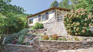 A stone house with a tiled roof, surrounded by lush greenery and a small waterfall. - Amazing home in Bedousse (Bedousse)