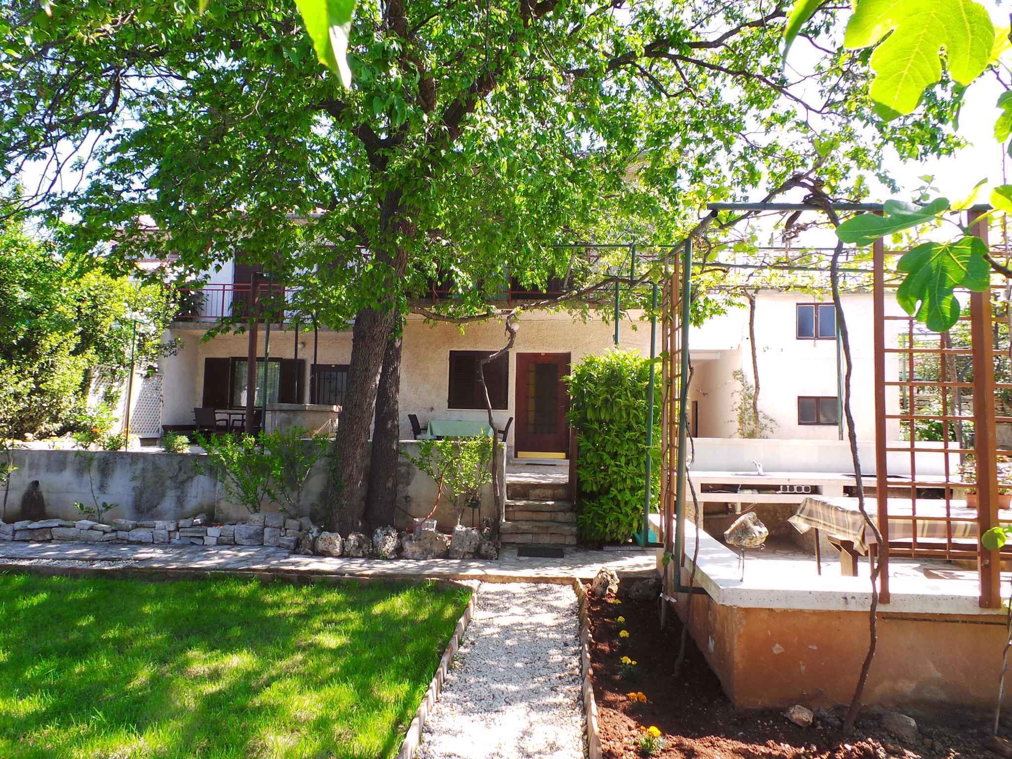 A residential building with a garden, a pergola, and a small outdoor seating area.