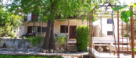 A residential building with a garden, a pergola, and a small outdoor seating area.