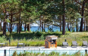 A pool area with lounge chairs, a small wooden structure, and a view of the sea. - Gorgeous apartment in Binz with indoor swimming pool (Prora/Rügen)