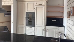 A kitchen with white cabinets, a black countertop, and a stainless steel sink. - Fewo Star - Windland Ranch - Riding stables with vacation apartments (House 3) (Altenkirchen)