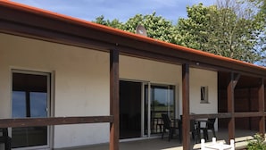 A covered outdoor area with a patio, a table with chairs, and a small white sign with a shield emblem. - Fewo Star - Windland Ranch - Riding stables with vacation apartments (House 3) (Altenkirchen)
