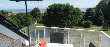 A balcony with a table set for breakfast, a wicker chair, and an umbrella.