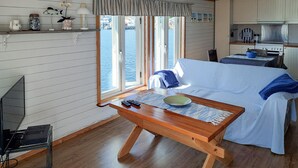 Una habitación acogedora con una mesa de madera, un sofá y vistas al mar a través de amplias ventanas.