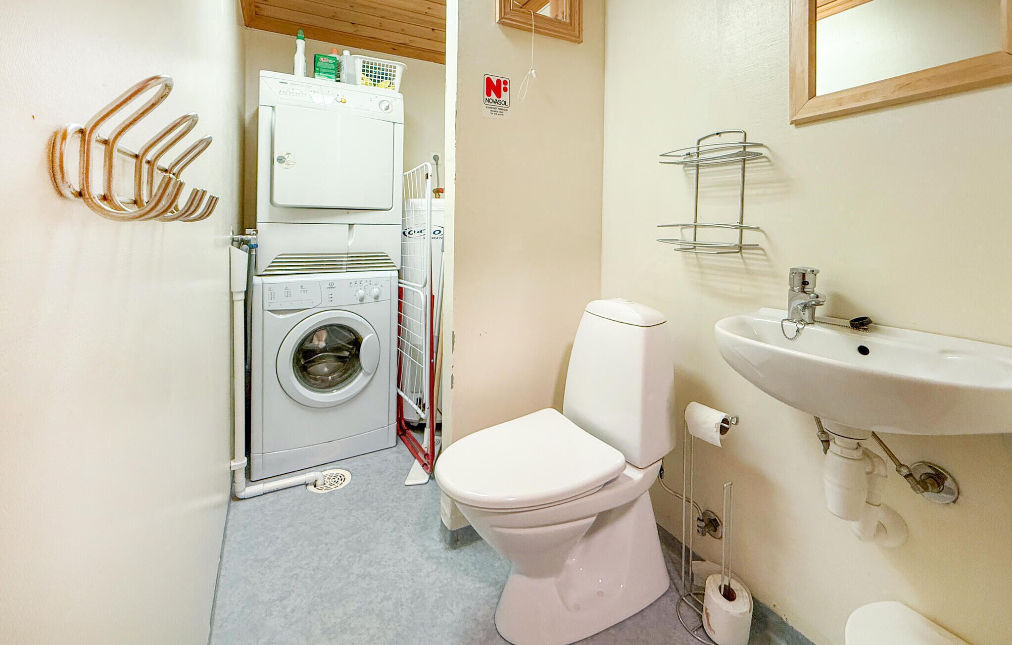 A compact bathroom with a washing machine, toilet, and sink.