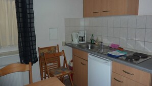 Una pequeña cocina con cafetera, lavamanos y armarios de madera.