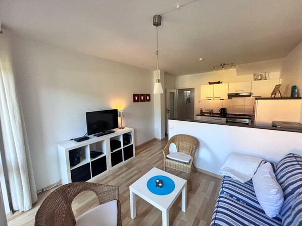 A modern living room with a flat-screen TV, a white entertainment unit, a dining table, and a sofa. - Zempin Ostseepark WE 34 Island Usedom only 150m to the beach - WE 34 (Zempin)