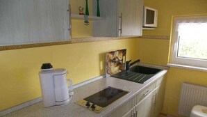A compact kitchen with a sink, a coffee maker, and a window. - Apartment 02 - Apartments Oechsner (Heringsdorf)