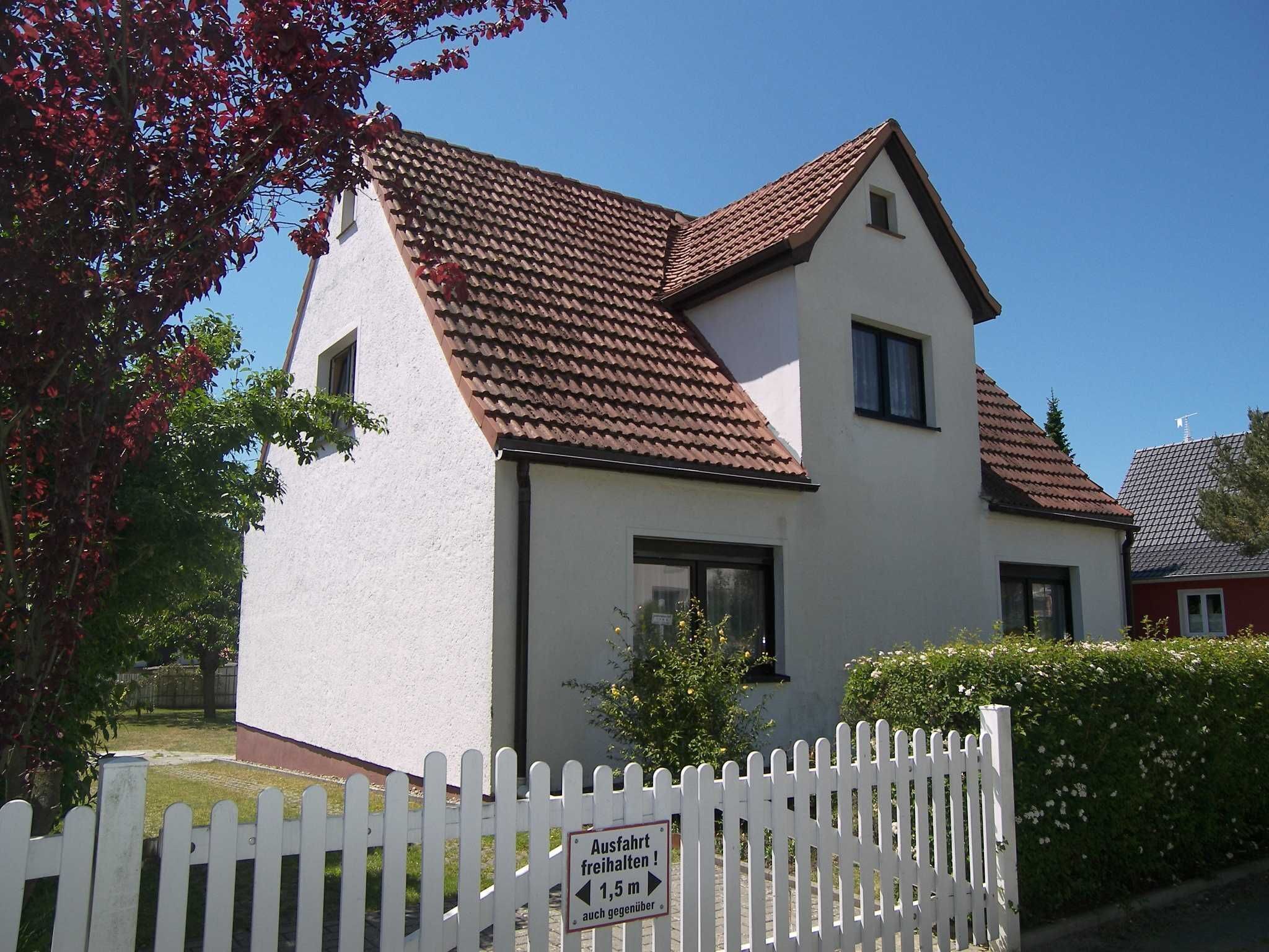 A two-story house with a red-tiled roof and a white exterior.