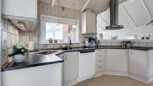 Een moderne keuken met witte kasten, een roestvrijstalen spoelbak en een groot raam voor natuurlijk licht.