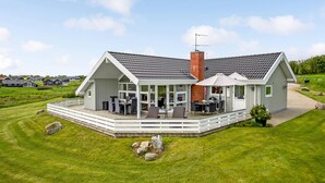Een modern huis met een groot terras, een overdekte patio en een bakstenen schoorsteen.