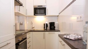 A compact kitchen with white cabinets, a microwave, a coffee maker, and a sink. - Holiday apartment with balcony only 200 m to the Baltic Sea beach (Wendtorf)