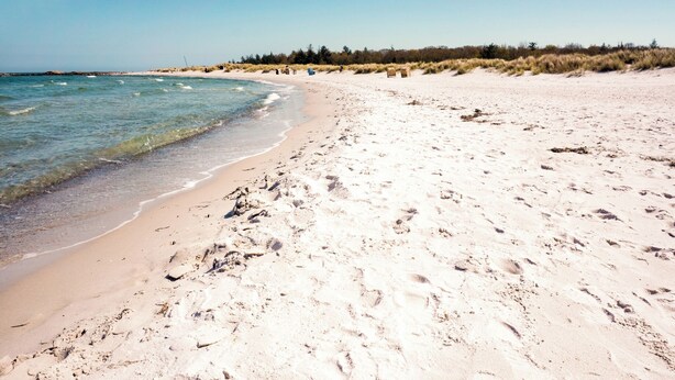 A sandy beach with clear water, a few footprints, and some dunes in the background. - Holiday apartment with balcony only 200 m to the Baltic Sea beach (Wendtorf)