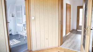 A hallway with wooden panel walls, a white radiator, and a white sink in a bathroom.