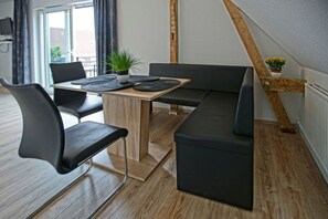 Une pièce moderne avec une table à manger en bois, des chaises noires, un canapé noir et une plante en pot.