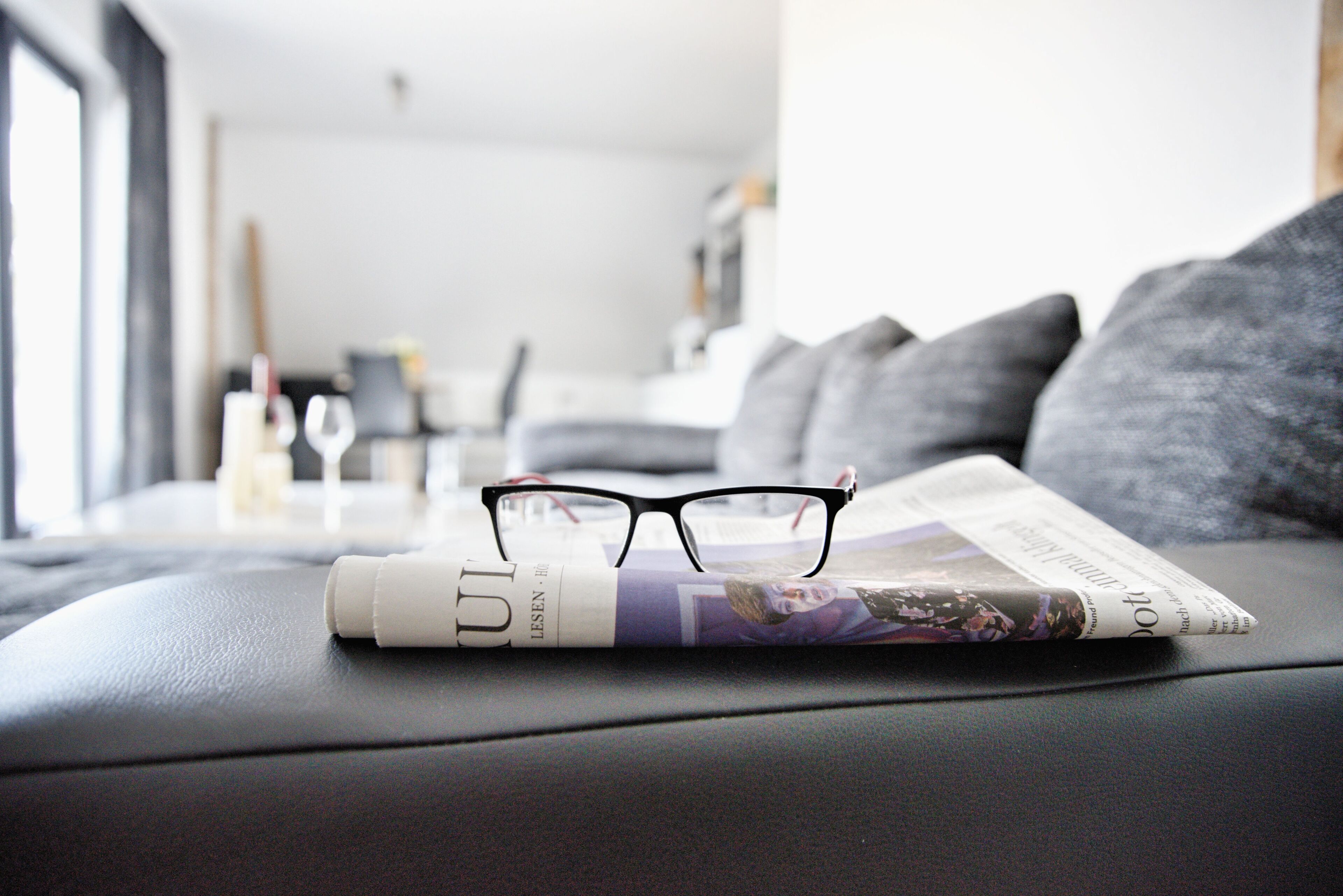 Una revista con lentes sobre un sofá en una sala de estar.