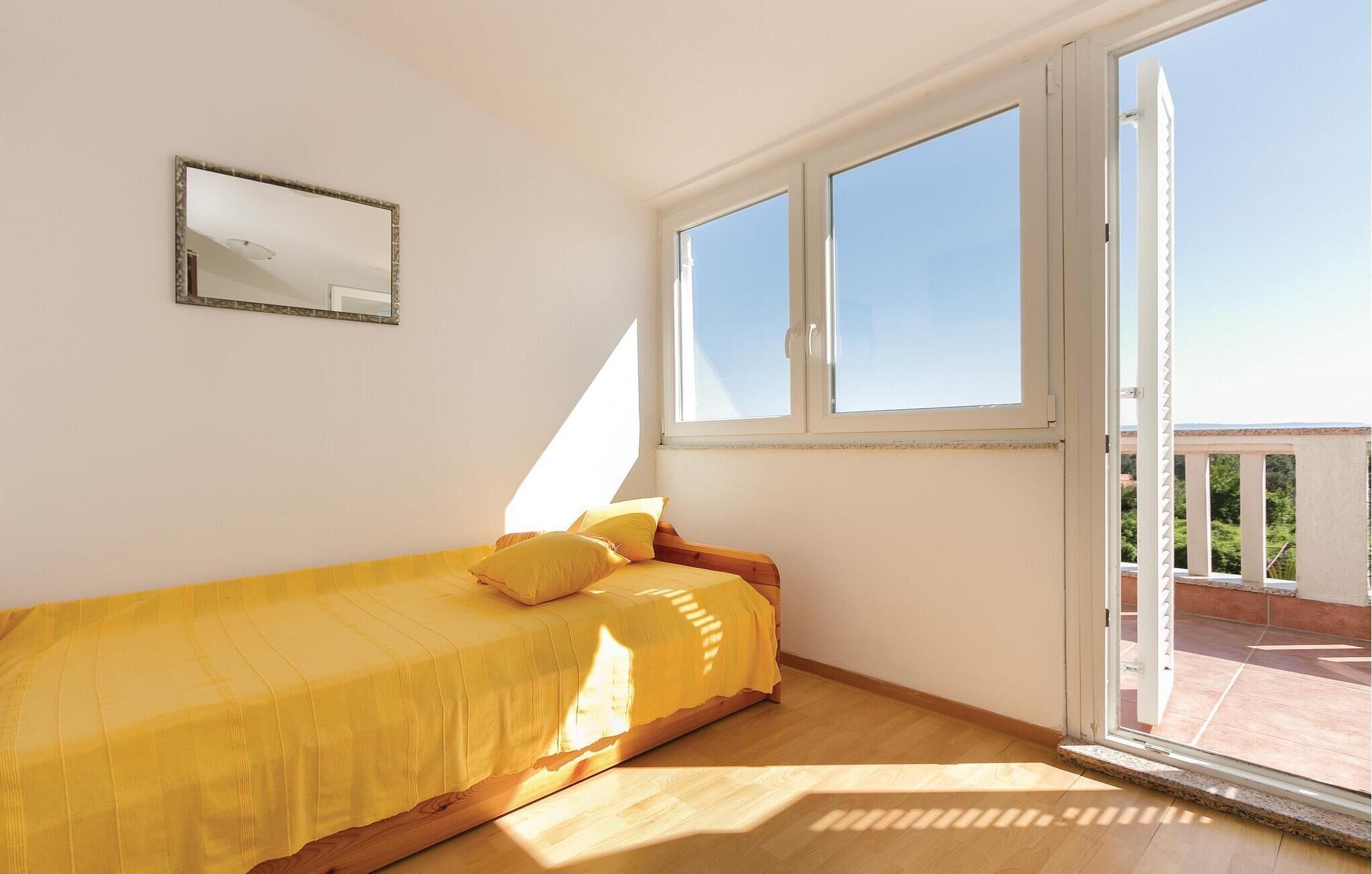 A bedroom with a bed, a window, and a balcony.