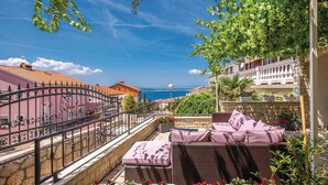 A balcony with wicker furniture, a view of the sea, and a stone wall. - Beautiful apartment in Crikvenica (Crikvenica)