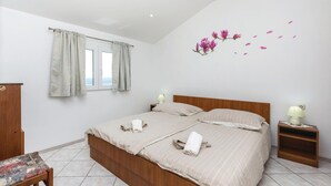 A bedroom with a bed, two bedside tables, a chair, a window with curtains, and a wall decal of flowers. - Beautiful apartment in Crikvenica (Crikvenica)