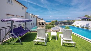 A poolside area with a view of the sea, two white lounge chairs, a purple umbrella, and a small table. - Beautiful apartment in Crikvenica (Crikvenica)