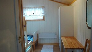 Ein kleiner, kompakter Raum mit Etagenbett, Holztisch, Heizkörper und einem Fenster mit Vorhang.