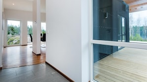 A spacious interior with a wooden floor, large windows offering a view of greenery, and a modern design. - Beautiful home in Holmsjö with WiFi (Holmsjö)