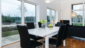 A modern dining area with a white table, black chairs, and a vase with flowers. - Beautiful home in Holmsjö with WiFi (Holmsjö)