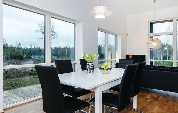 Un comedor moderno con una mesa blanca, sillas negras y un jarrón con flores.