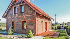 Una casa de ladrillo de dos pisos con techo rojo, una antena parabólica y un pequeño porche.