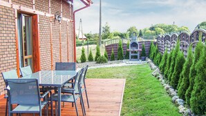 Un patio con una mesa, sillas, un muro de ladrillo y una terraza de madera.