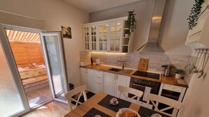 A modern kitchen with white cabinets, a wooden countertop, and a dining area with a table set for two.