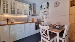 A modern kitchen with white cabinets, a wooden countertop, and a dining area with white chairs and a table.