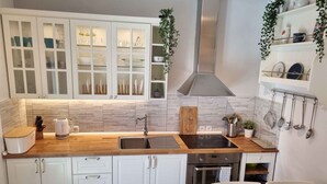 A modern kitchen with white cabinets, a stainless steel range hood, a built-in oven, and a black induction cooktop.