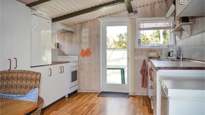 A compact kitchen with white cabinets, a wooden floor, and a view through a door to an outdoor deck. - 3 bedroom beautiful home in Sæby (Sæby)