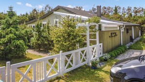 A house with a white fence, a wooden deck, and a car parked in front. - 3 bedroom beautiful home in Sæby (Sæby)