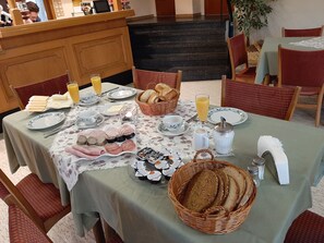 A breakfast table set with plates, bread, pastries, and beverages. - Double room 1 - Gasthaus Pension Schumbert (Erbach)