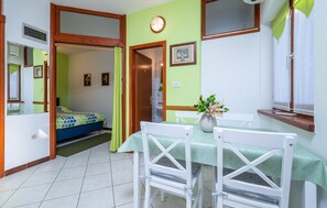 A room with a bed, a dining table with chairs, a vase with flowers, and a window with curtains. - Beach front apartment in Vodnjan (Vodnjan)