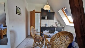 Ett kompakt bostadsutrymme med en matplats, ett litet kök och utsikt över omgivningen.