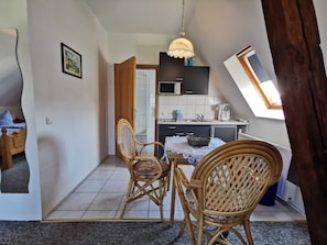 A compact living space with a dining area, kitchenette, and a view of the outside.