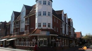 Un edificio de varios pisos con una torre destacada, probablemente un hotel, que tiene una entrada a nivel de calle con área cubierta y ventanas visibles.
